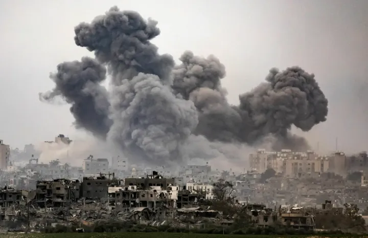 Image of Gaza in late October, showing black cloud of smoke over the ruins of a destroyed G